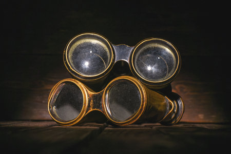 Retro binoculars on the old wooden desk table background front view close up. Travel background.の写真素材