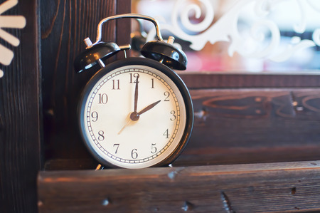Old alarm clock standing on a wooden surface in the background mirrorの写真素材