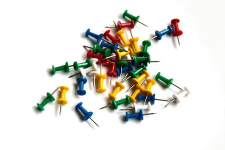 Bright multicolored office pins in the heap on white 