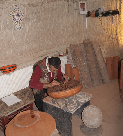A man in a workshop carving the ornament on the claywareのeditorial素材