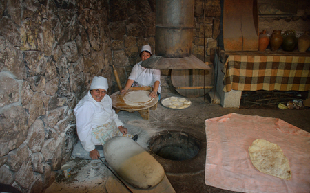 Women making traditional armenian lavash bread (thin wheat pastry) in the underground oven with a special pillow. のeditorial素材