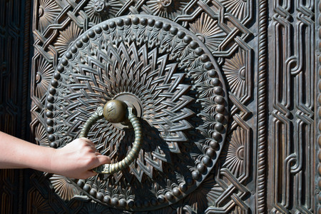 The old decorated metal doorknob with a man hand. Matenadaran, Armeniaの写真素材