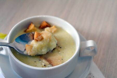 spoon with creamy celery soup over the bowl