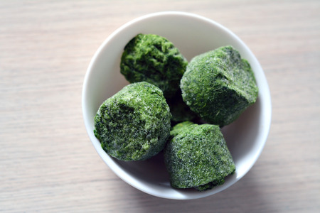 fresh frozen cubes of spinach in a bowlの写真素材