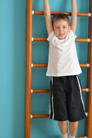 boy hangs off the ladder ready to jumpの写真素材