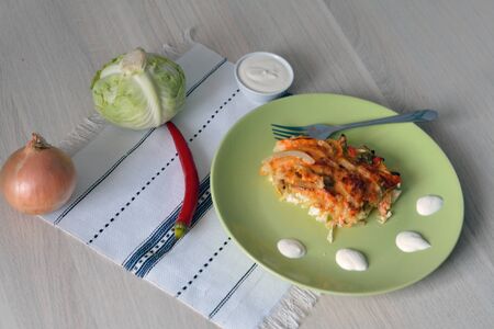 spicy cabbage casserole with raw vegetables on the tableの写真素材