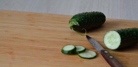 wooden board with a  knife and cucumbersの写真素材