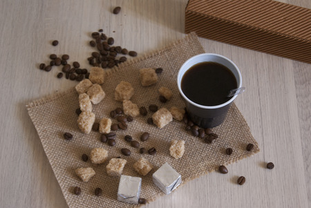 Plastic cup with coffee, beansd and chocolates in silver foil on the sackclothの写真素材