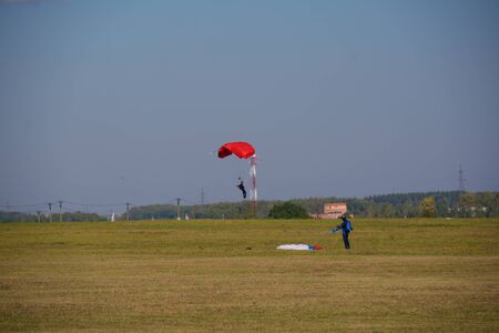 Man parachuting near the ground and a man folding the parachuteの写真素材