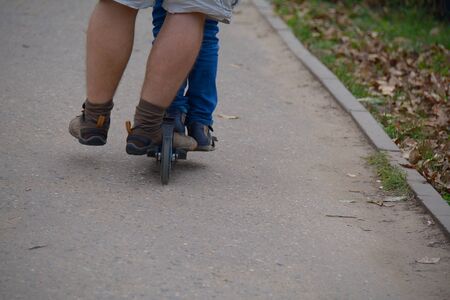 Legs of two people on one scooter, from the back