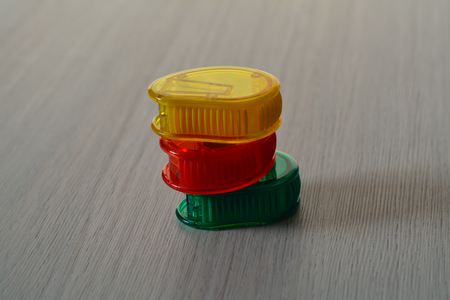 Three bright plastic sharpeners on the wooden table, in a pileの写真素材