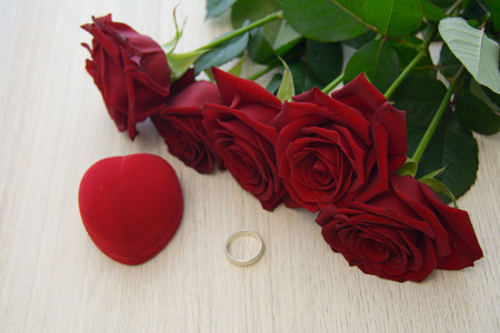 one silver ring on the table, with red roses and a boxの写真素材