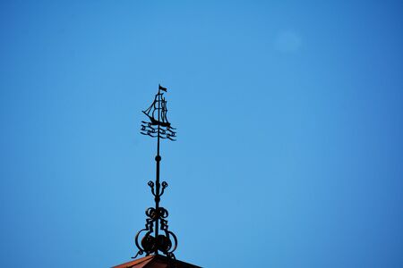 black metal spire in the form of the ship on the roof