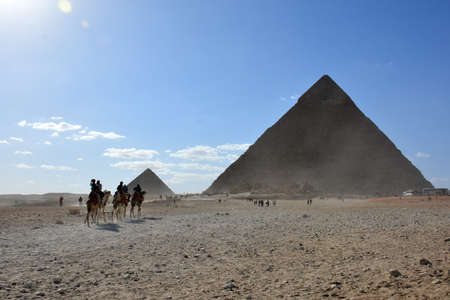 GIZA/EGYPT, NOVEMBER 30, 2018: small group of tourists, riding on the camels in the desert, next to the pyramidsのeditorial素材
