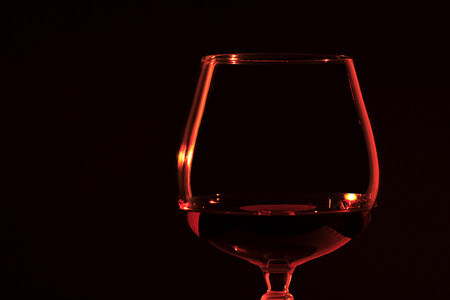 Bourbon in a brandy snifter lit only by candlelight in front of a black backgroundの写真素材