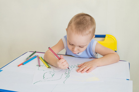 Little boy at a desk learning to draws with pencils. Child with a pencil in hand. Photo with copy space and limited depth of field.の写真素材