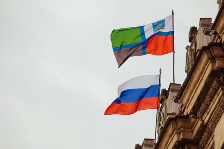 Flags of the Russian Federation and the Belgorod region waving on the parapet of the administrative building of the Soviet Stalinist architectureの写真素材