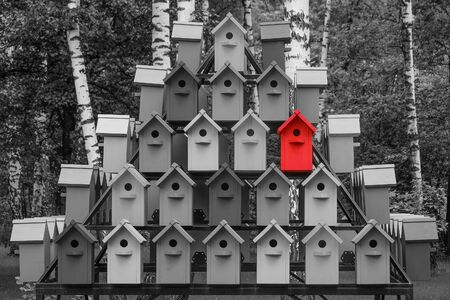 Red color wooden birdhouse stand out from the crowd. Metaphor to business concept. Stands out among...