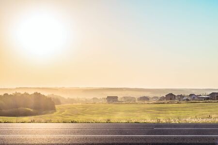 Roadside rural landscape in light of the low evening sun backlight. View from the road of a Russian...