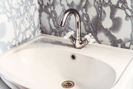Chromed silvery washbasin with bright white sink and two valvesの写真素材