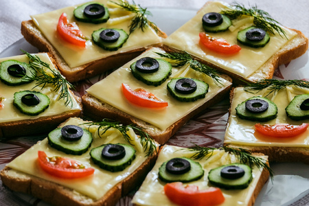 Funny smiling sandwiches with face from cucumbers, tomato, olive and dill. Perspective view with selective focus.の写真素材