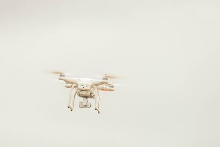 White drone with video camera flying in the sky