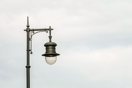Black metal vintage street lamp on a cloudy sky background. Background with copy space.の写真素材