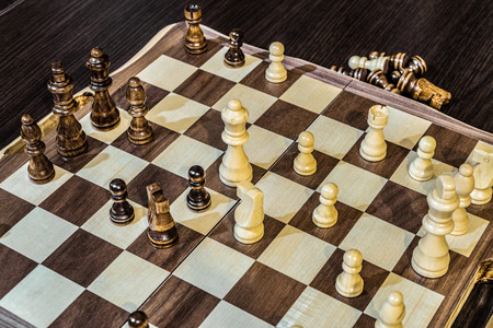 Wooden chess Board and chess pieces in in the game. Limited depth of field.