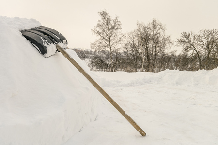 Snow shovel on a high snowdrift near countryside road. Shovel for cleaning the footpaths from snow.の写真素材