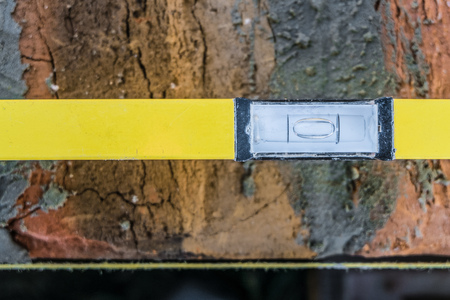 Yellow bubble level lies on brick masonry wall with lacing cord. Bubble centered. Fragment close-up. Top view.の写真素材
