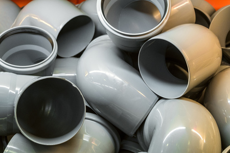 Plastic pipe bends in a pile. Industrial products for construction.の写真素材