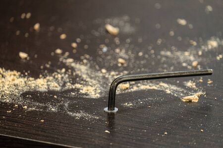 Hexagonal furniture key in a twisted bolt. Laminated chipboard sheet wenge color. Furniture assemble close-up.の写真素材