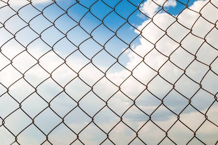 Metal chain links wire-mesh rabitz on a blue cloudy sky background