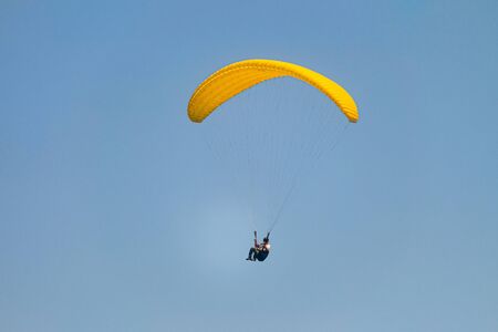 Flight on a yellow paraglider in blue sky