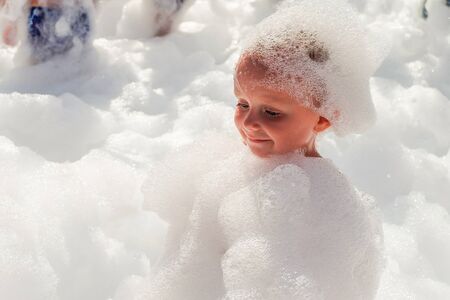 Little boy in airy foam on a dance party floor. Foamy children disco party.