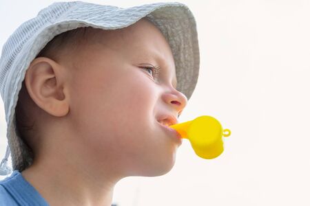 Little boy in a panama hat with a yellow whistle in his mouthの写真素材