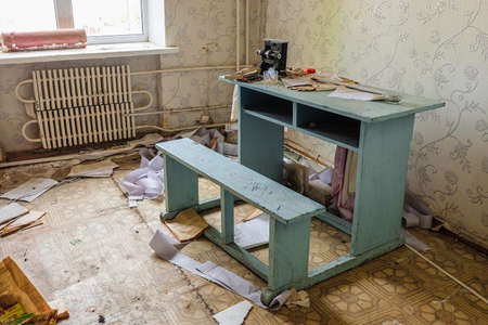 Room of an old abandoned building filled with trash on the floor and wooden deskの写真素材