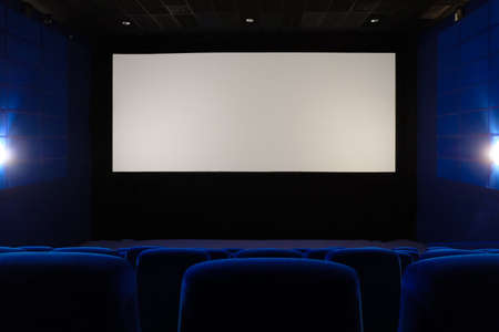 Empty cinema hall. View of empty white cinema screen from the upper rows of the auditorium.の写真素材
