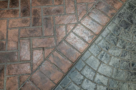 Dark pavement with red and gray tiles. Footpath paved with tiled stone.