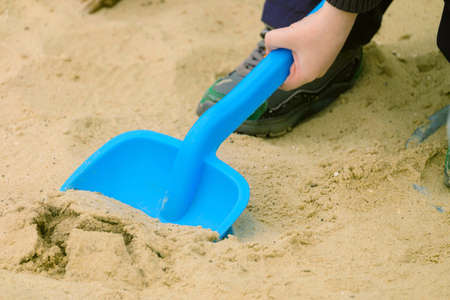 Child playing with sand and plastic shovelの写真素材