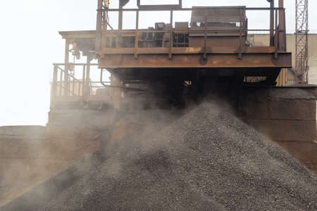 Iron ore pellets are piled from the conveyor belt into a heap. Falling of spherical lumps of crushed...