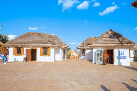 Belgorod, Russia - August 23, 2023: Toy stores in the new Belgorod amusement attractions park Kaleidoscope. Houses with a thatched roof in a South Slavic rural style.のeditorial素材
