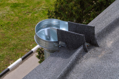 Metal galvanized water inlet funnel on the edge of a soft flat roll roof. External organized...