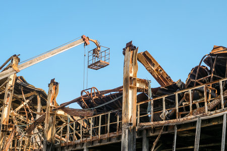 Auto crane cradle for workers and destroyed by fire industrial building. Dismantling works.