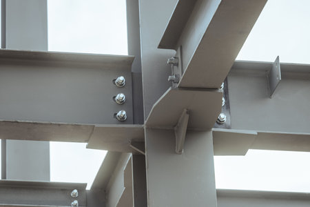 Mounting bolted connection of steel beams before welding. Metal construction covered protective gray...