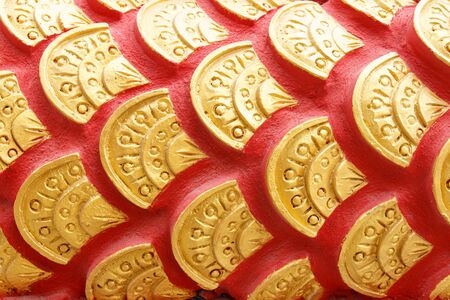 a row of naga s scale which sculpted on concrete and paint with red and gold color 