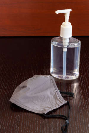a bottle of hand sanitizer and a reusable face mask. These items can help to reduce and prevent the spread of the Covid-19 Coronavirusの写真素材