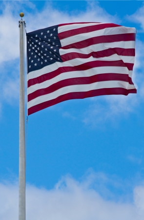 American flag blowing in the wind with a blue sky backgroundの写真素材