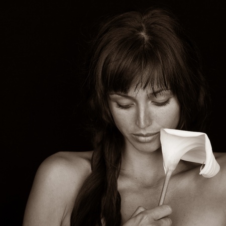 Sepia toned portrait of a young girl holding a white calla lily.の写真素材