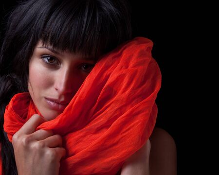 Beautiful young woman with a red shawl, isolated on black.の写真素材